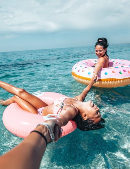 mother-daughter-happy-swimming-in-the-sea-with-inflatable-doughnut-on-beautiful-sunny-day
